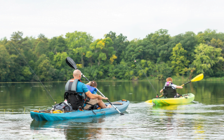 father and two children in kayaks with fishing rods