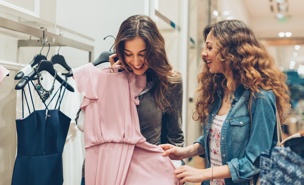 Two young women choosing dresses in a luxury fashion store