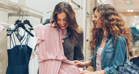 Two young women choosing dresses in a luxury fashion store