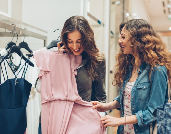 Two young women choosing dresses in a luxury fashion store