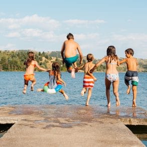 kids jumping in lake off a pier