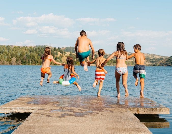 kids jumping in lake off a pier