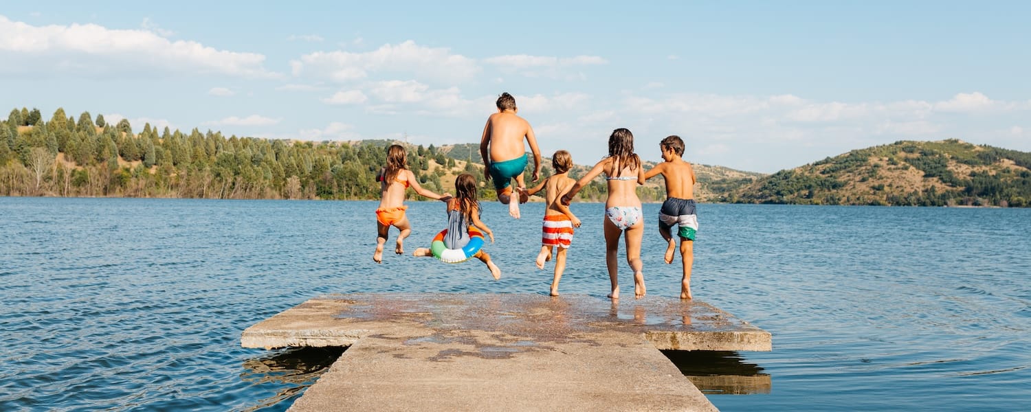 kids jumping in lake off a pier